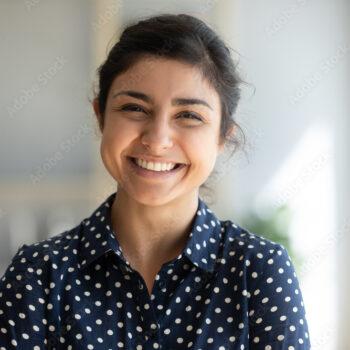 Cheerful indian girl standing at home office looking at camera